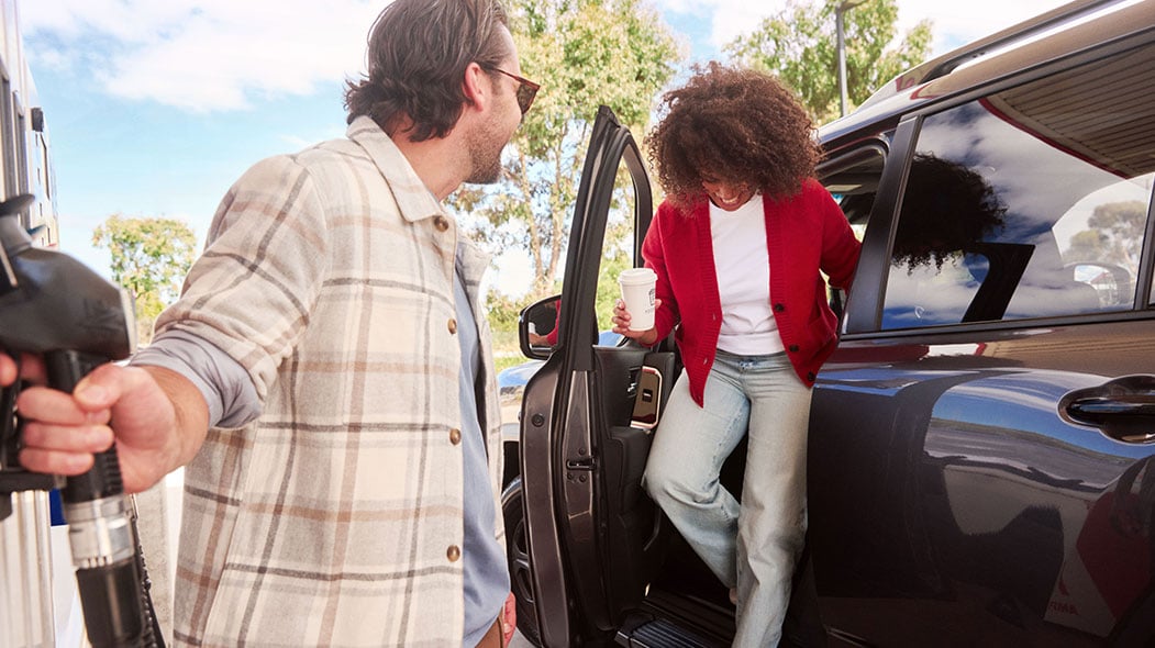 Woman getting out of car with coffee in hand